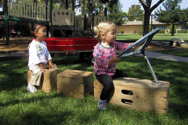 Two girls pretending to drive in the yard